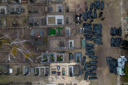 Policías trabajan para identificar civiles asesinados durante la ocupación rusa en Bucha, Ucrania, a las afueras de Kiev, antes de enviar los cuerpos a la morgue, el miércoles 6 de abril de 2022. (AP Foto/Rodrigo Abd)