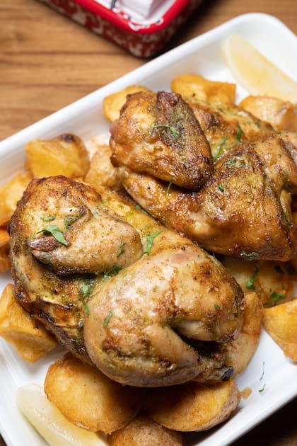 Pollito de 900 gramos y piel crocante, servido con papas doradas.