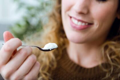 Portrait of beautiful young woman eating yogurt at home.
