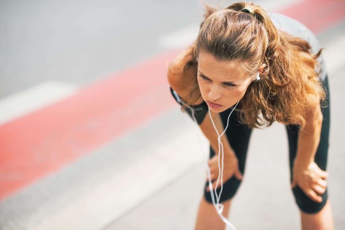 Portrait of tired fitness young woman outdoors in the city catching breathe