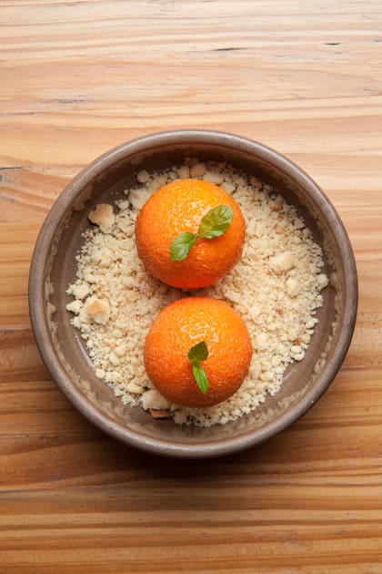 Postre en Bruta: cheesecake de naranja, nada tradicional: esferas de queso crema y chocolate blanco, glaseado de orange curd sobre una arena de masa sucré.