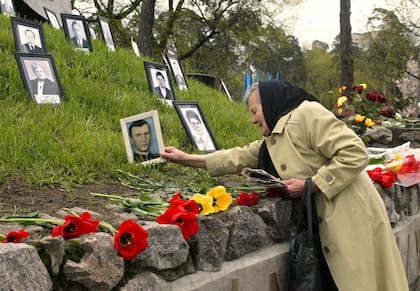 Praskoviya Nezhyvova coloca una foto de su hijo, Viktor, que murió tras las operaciones de limpieza de la explosión, en un monumento a las víctimas en Kiev