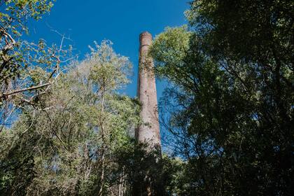Como vestigio de lo que supo ser un proyecto industrial que duró muy poco, se erige una espectacular chimenea que sale del medio del monte