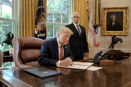 President Donald Trump, joined by Vice President Mike Pence, signs an executive order imposing more sanctions on Iran inside the Oval Office at the White House in Washington, on June 24, 2019. “We will continue to increase pressure on Tehran,” Trump said as he sat at his desk preparing to sign an order. “Never can Iran have a nuclear weapon.” (Gabriella Demczuk/The New York Times)
