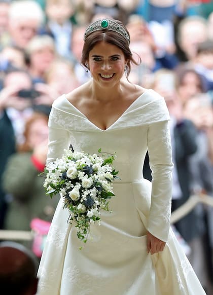 Radiante, sin velo y rompiendo tradiciones, Eugenia llevó un vestido de doble escote en "V" y falda abullonada, de Peter Pilotto. Sobre la falda, en brocado, la rosa de York, un guiño a la Reina; el trébol de Irlanda, origen de la familia Ferguson, y la hiedra, signo de su casa.