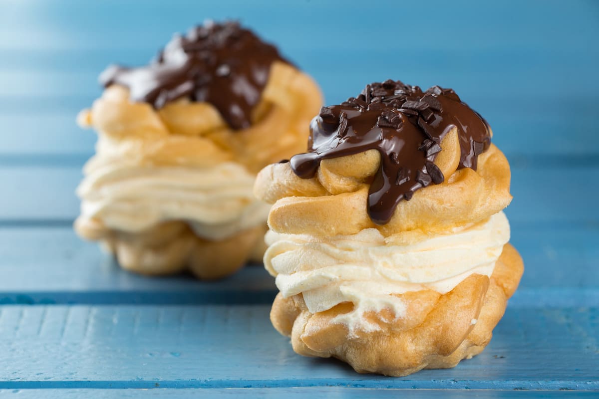 Profiteroles rellenos de crema chantilly y baño de chocolate.
