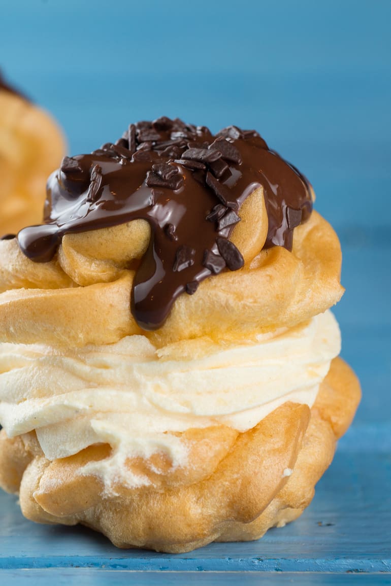 Profiteroles rellenos de crema chantilly y baño de chocolate.