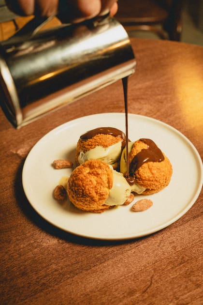 Profiteroles rellenos de helado de pistacho, con chocolate tibio y praliné de almendras