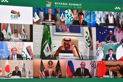 Proyectado en una pantalla en el Centro Internacional de Medios en la capital de Arabia Saudita, Riad, el 21 de noviembre de 2020, el rey saudí Salman bin Abdulaziz da un discurso de apertura de la cumbre del G20, que se celebró virtualmente debido a la pandemia de coronavirus, mientras que lo rodea