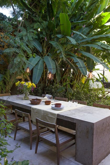 Proyectando los almuerzos y comidas en exteriores, Par Estudio propuso una mesa de cemento a la sombra de las plantas.
