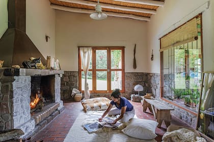 Guadalupe trabaja en su nueva muestra frente al enorme hogar del living. Pufs con fundas de telar y manta (Illari, de Magdalena Sánchez de Bustamante). En el rincón, lámpara de resina (Sariri, Jujuy).