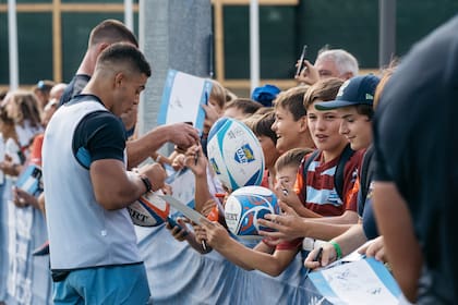 Pumas dando autógrafos a chicos; el rugby se mantiene cerca de los jóvenes, que son prioritarios para el deporte.