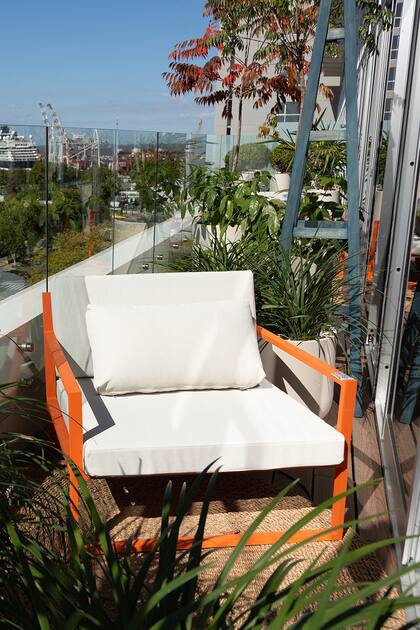 Puro diseño en el balcón del departamento ambientado por Gaby López Monzón: Sillón individual Prana naranja con mesas Stark en gris.