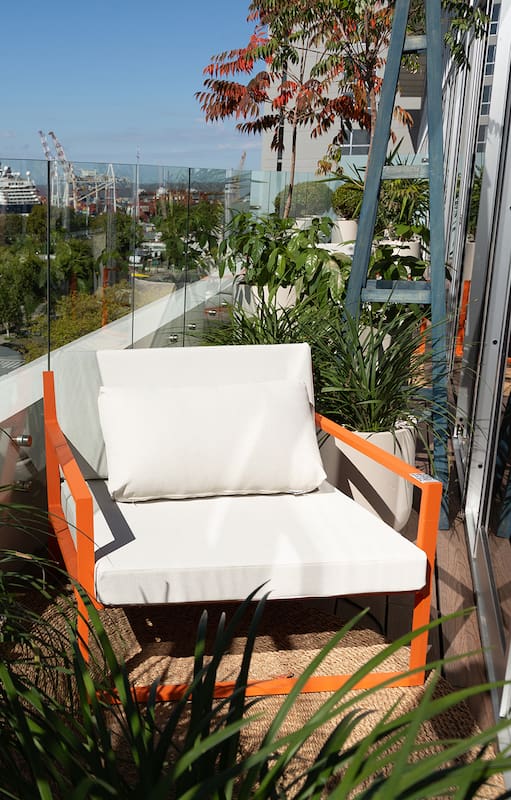 Puro diseño en el balcón del departamento ambientado por Gaby López Monzón: Sillón individual Prana naranja con mesas Stark en gris.