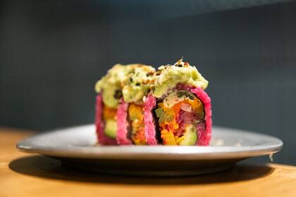 Purple Veg: Verdeo en tempura, palta y mix de vegetales encurtidos, envueltos en arroz infusionado en remolacha, coronado con avocado smash.