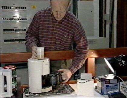 Quentin Stafford-Fraser muestra la cafetera para un programa de TV en 1998; se puede ver la cámara que la enfoca en forma permanente, y atrás una lámpara que la ilumina