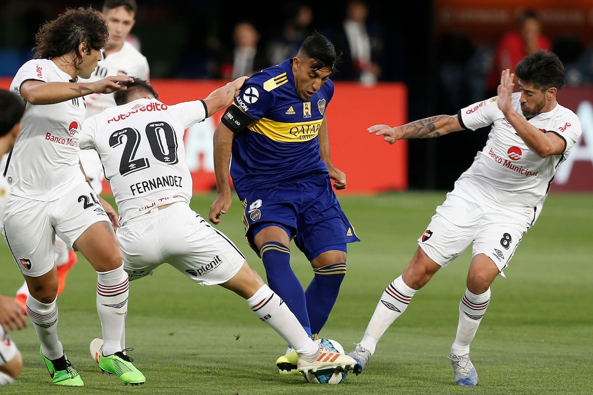 Ramón Abila, de Boca, disputa la pelota con Pablo Pérez y Julián Fernández, de Newells.
