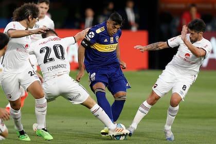 Ramón Abila, de Boca, disputa la pelota con Pablo Pérez y Julián Fernández, de Newells.