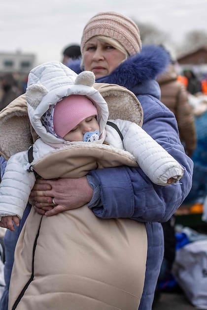 Una mujer sostiene a un bebé mientras ciudadanos ucranianos llegan al paso fronterizo peatonal de Medyka huyendo del conflicto en su país, en el este de Polonia el 27 de febrero de 2022.