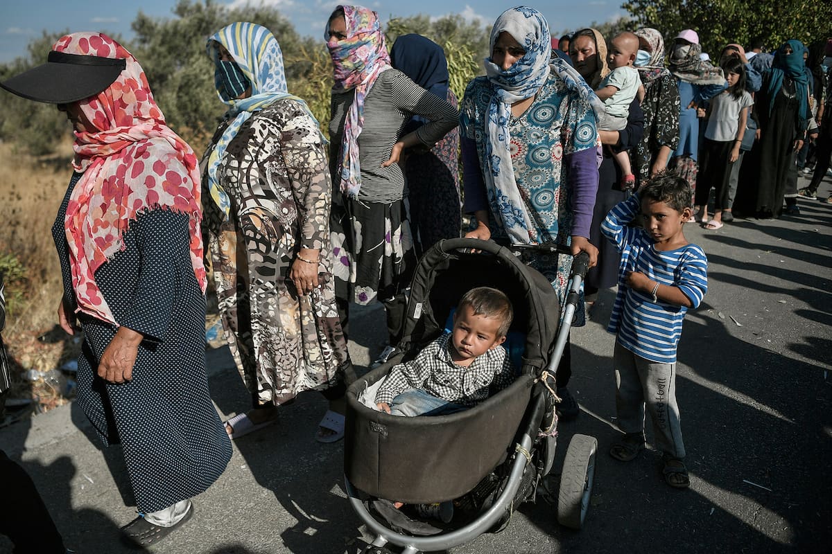 Refugiados y migrantes esperan la distribución de alimentos en una carretera donde miles viven sin refugio, cerca del campamento Kara Tepe en la isla de Lesbos el 13 de septiembre de 2020