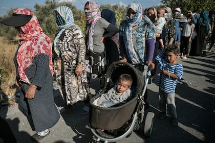 Refugiados y migrantes esperan la distribución de alimentos en una carretera donde miles viven sin refugio, cerca del campamento Kara Tepe en la isla de Lesbos el 13 de septiembre de 2020