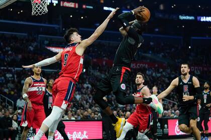Reggie Jackson (1), de los Clippers de Los Ángeles, lanza a canasta ante su rival de los Wizards de Washington Deni Avdija (9) en la primera mitad del juego de la NBA que enfrentó a ambos equipos, en Los Ángeles, el 9 de marzo de 2022. (AP Foto/Ashley Landis)