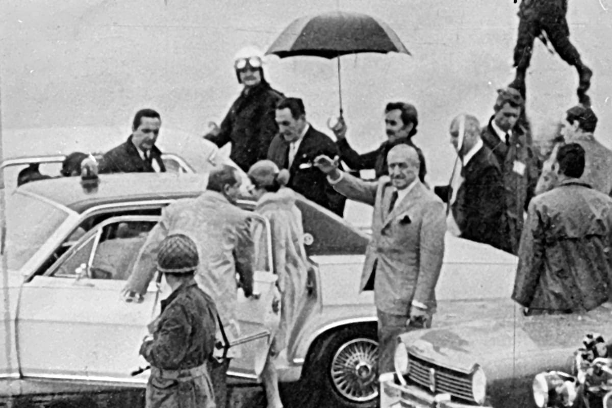 Regreso de Perón a la Argentina, Juan Ignacio Rucci con un paraguas resguarda a Perón de la lluvia, detrás de Rucci está López Rega sobre el lado derecho del auto que los trasladará, del lado izq. está subiendo Isabel Perón y la sigue José Cámpora. 17 de noviembre de 1972.
