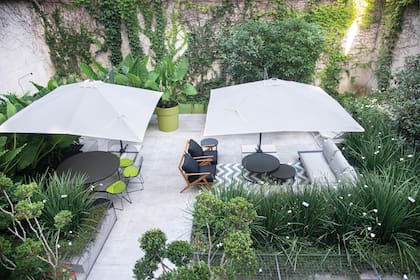 Reproducir en exteriores un comedor y un living, rodeados del verde en movimiento que nos proporcionan los Dietes grandiflora. Sombrillas cuadradas para que, en las horas de sol, también pueda aprovecharse al máximo este espacio.