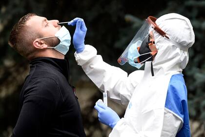 República Checa, Kolín: un trabajador de la salud que usa un traje protector toma un hisopo de un hombre para una prueba de Coronavirus