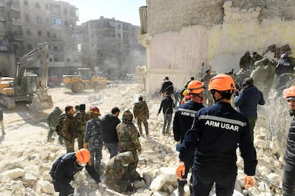 Rescatistas armenios y soldados sirios buscan víctimas y sobrevivientes entre los escombros de un edificio derrumbado en la ciudad septentrional de Alepo, días después de que un mortífero terremoto sacudiera Turquía y Siria, el 9 de febrero de 2023.