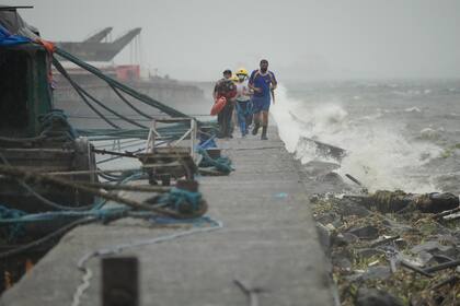 Rescatistas corren mientras revisan a residentes que viven en el distrito costero de Tondo en momentos en los que el tifón Noru se acerca a Manila, Filipinas, el domingo 25 de septiembre de 2022. (AP Foto/Aaron Favila)