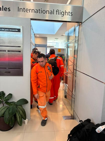 Rescatistas de distintas organizaciones pasan por migraciones antes de abordar el avión piloteado por Enrique Piñeyro