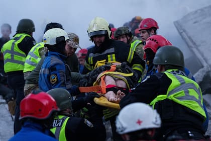 Rescatistas trasladan en camilla a una mujer herida desde una vivienda que sufrió importantes daños tras un ataque ruso a un vecindario residencial en Kiev, Ucrania, el 14 de mayo de 2026. (AP Foto/Evgeniy Maloletka)