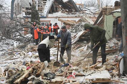 Rescatistas y residentes locales limpian los escombros tras los ataques rusos, en Zmiiv, región de Kharkiv, el 8 de enero de 2024, en medio de la invasión rusa de Ucrania.
