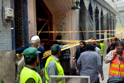 Rescatistas y voluntarios, a las puertas de una mezquita donde se produjo un ataque con bomba, en Peshawar, Pakistán, el 4 de marzo de 2022. (AP Foto/Muhammad Sajjad)