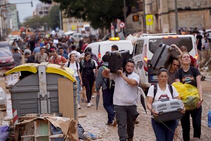 Residentes cargan con sus pertenencias tras abandonar sus viviendas, afectadas por las inundaciones en Valencia, España, el 31 de octubre de 2024. (AP Foto/Alberto Sáiz)