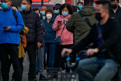 Residentes con mascarilla esperan en fila para someterse a una prueba rutinaria de detección del COVID-19, en Beijing, el 25 de octubre de 2022. (AP Foto/Andy Wong)