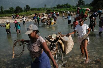 Residentes cruzan el río Cavaillon para llegar al mercado de Maniche y vender sus productos, en Maniche, Haití, el 24 de agosto de 2021, una semana después de un sismo de magnitud 7,2 que remeció la zona. (AP Foto/Matías Delacroix)