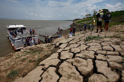 Residentes de una comunidad ribereña cargan alimentos y recipientes con agua potable tras recibir ayuda debido a la constante sequía en Careiro da Varzea, estado de Amazonas, Brasil