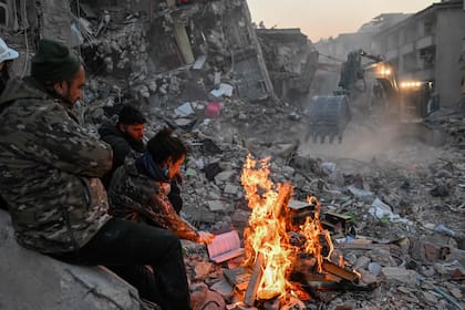Residentes locales queman libros para mantener el calor entre los escombros en Hatay, Turquía