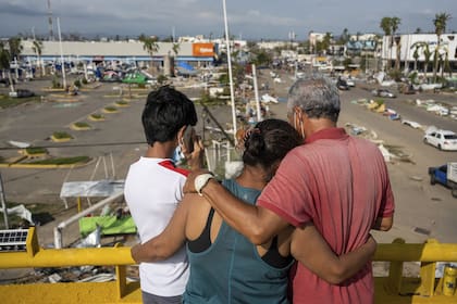 Residentes, parados en un paso elevado, observan los daños causados por el huracán Otis en Acapulco