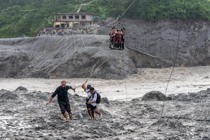 Residentes utilizan una tirolesa recién instalada para ayudar a la gente a cruzar el río Trishuli