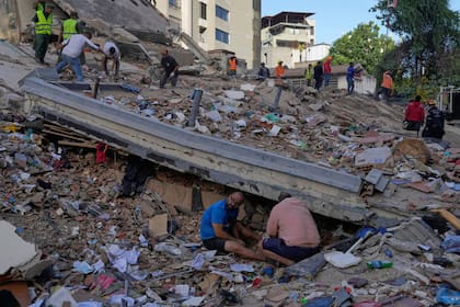 Residentes y equipos de rescate buscan entre los escombros de un edificio que colapsó a causa de los terremotos que sacudieron Caracas el día anterior