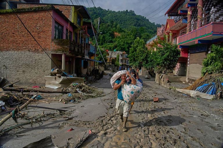 Residents carry their belongings as they walk to safer areas in the aftermath of flash floods in Devighat, in Nepal's Nuwakot district, Thursday, Aug. 27, 2026. (AP Photo/Niranjan Shrestha)