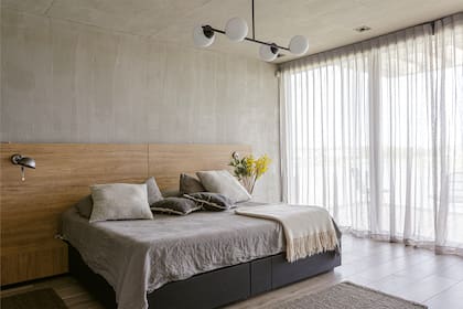 Respaldo de cama en placas de MDF enchapado en roble americano (Estudio Gambotto). Almohadones (Casa Chic). Lámpara colgante (San Isidro Luz). Cortinas Hunter Douglas (Arteplano).