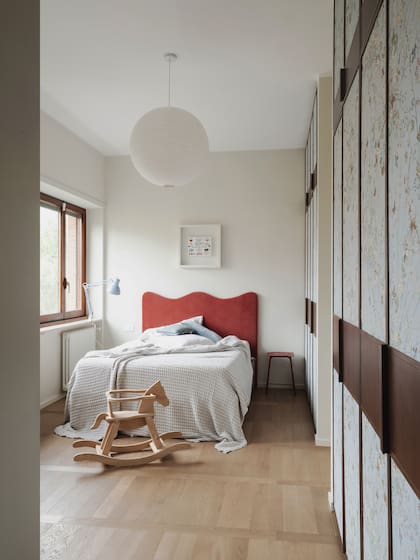 Respaldo de cama rojo y almohadones (L’Opificio). Revestimiento en papel tapiz de la colección (Disney Home).