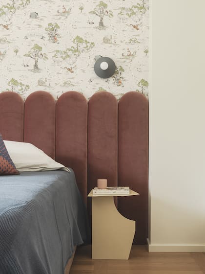 Respaldo de cama y almohadones (L’Opificio). Papel tapiz con motivos de Winnie Pooh (Disney Home), aplique de pared (Plato Design) y mesita de noche (Millim)