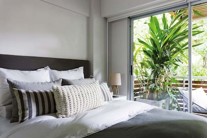 Respaldo forrado en lino. (Estudio Filcman Gurfinkiel). Ropa y accesorios de cama (Gutérrez Deco). A cada lado del balcón se puso una gran strelitzia, para darle a los ambientes su pantalla verde y tropical.