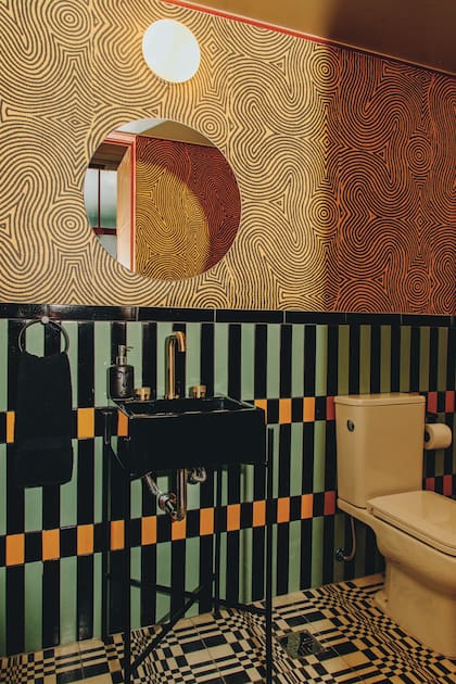Revestimiento de azulejos (Eme Carranza por Azul Marino), piso calcáreo (Eme, por Calcáreos Giacomozzi-Molinari), empapelado con hipnóticos trazos curvos (Eme Carranza). Grifería ‘Fabric Gold’ (Peirano).