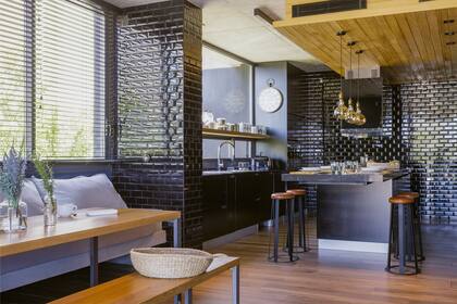 Revestimiento ‘Subway’ negro (Deco Baños y Cocinas). Bajomesada y bajoisla laqueados en negro. Cesta de fibras naturales (Claudia Adorno).